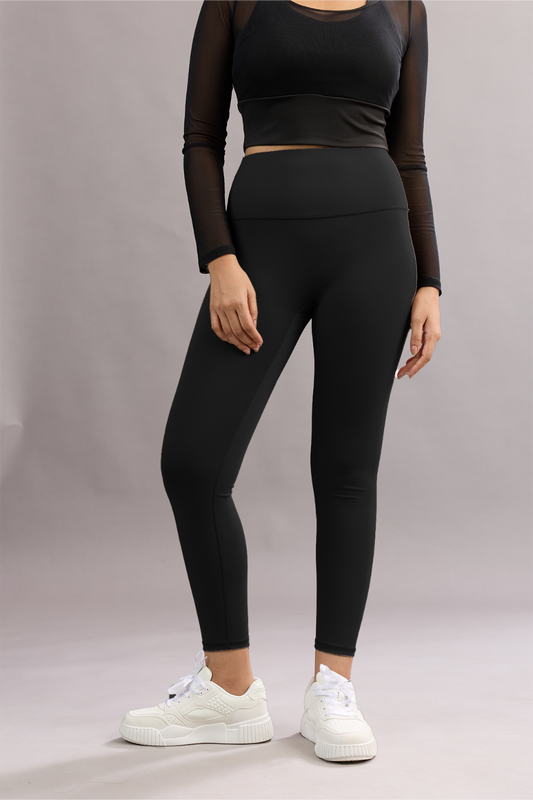 Person wearing a black athletic outfit with white sneakers on a plain background