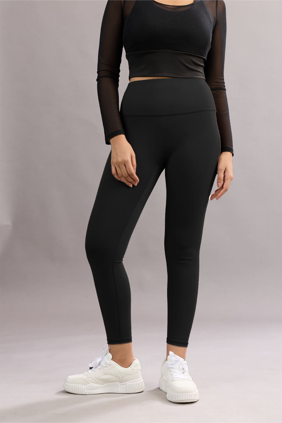 Person wearing a black athletic outfit with white sneakers on a plain background